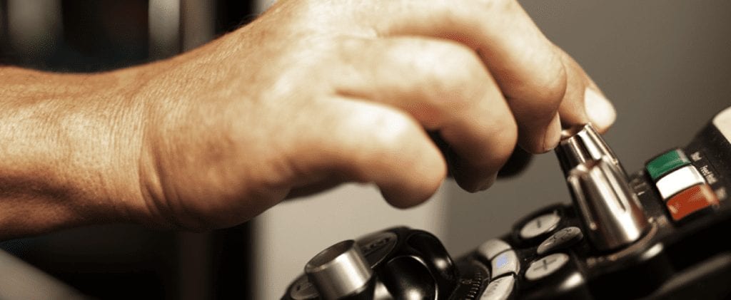 Hand working on the controls of a CNC machine