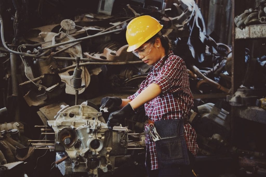Woman working on machine with safety hat and goggles